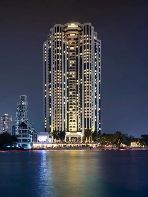 The Peninsula Bangkok tower lit up over the river at night via Expedia
