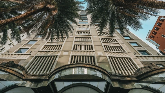 Hotel Muse Bangkok facade framed by palms via Expedia